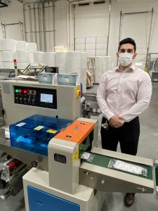Chaz Kovacks Stands in front of PPE mask making machine