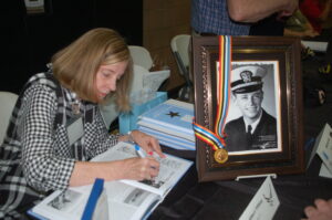 Cheralynn Beaudry signs the book in honor of her MIA father Albert Tiffany at the 2019 book reception.