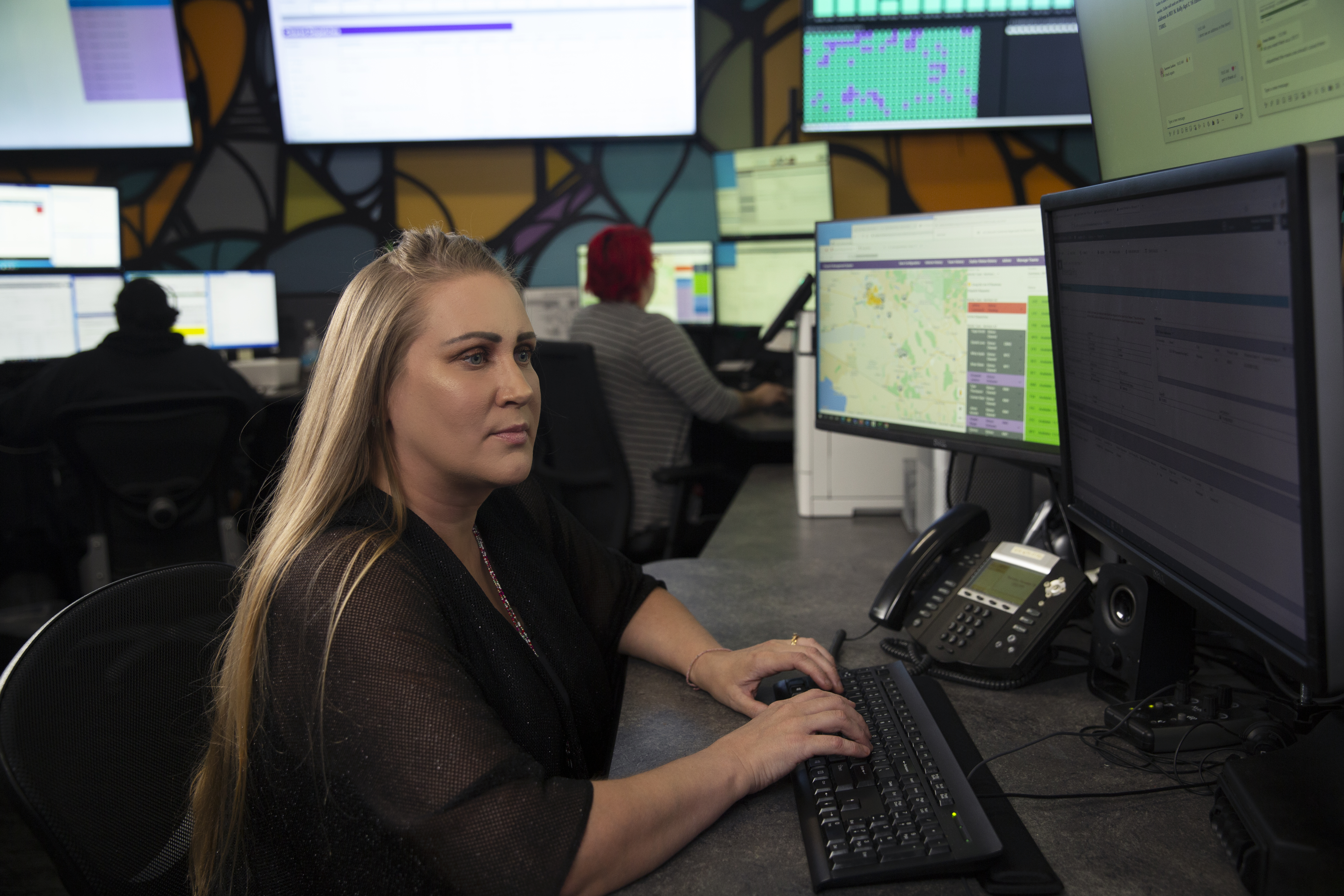 A crisis line worker sits in front of several computer screens ready to assist a caller.